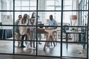 Successful business team. Full length of young confident business people discussing something while working behind the glass wall in the board room